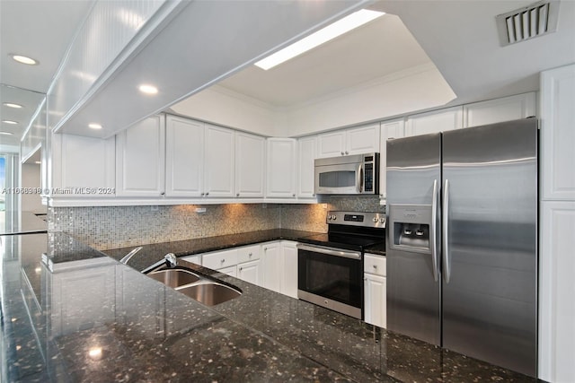 kitchen featuring tasteful backsplash, sink, white cabinetry, stainless steel appliances, and dark stone countertops