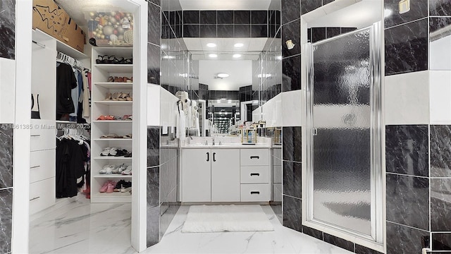 bathroom featuring a shower with door, vanity, and tile walls