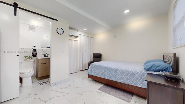 bedroom with a barn door, a wall unit AC, and connected bathroom