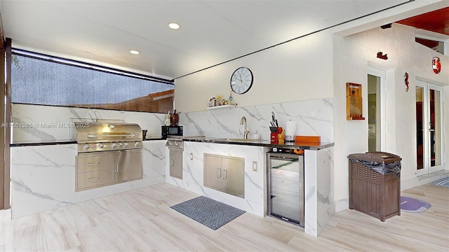 kitchen featuring backsplash, light hardwood / wood-style floors, sink, and wine cooler