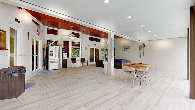 interior space featuring a towering ceiling, light wood-type flooring, and ceiling fan