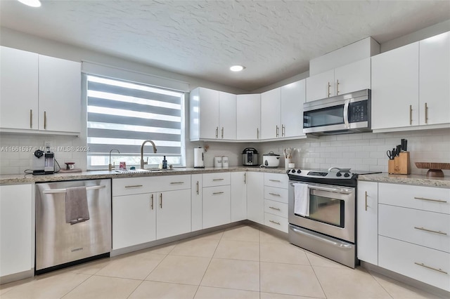 kitchen featuring stainless steel appliances, white cabinetry, a textured ceiling, and light tile patterned flooring