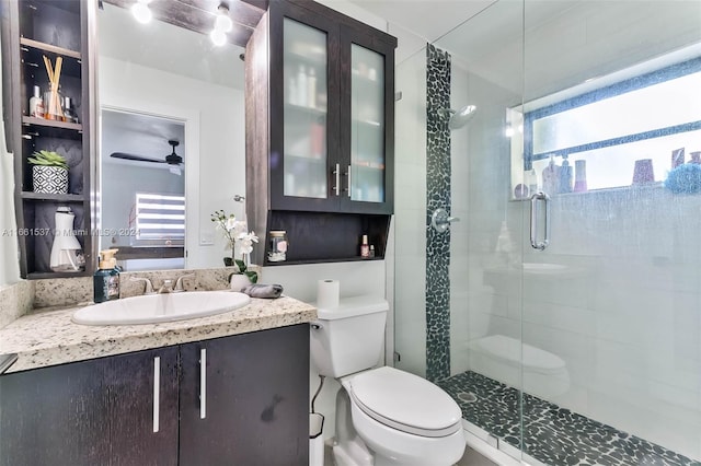 bathroom with walk in shower, vanity, toilet, and ceiling fan