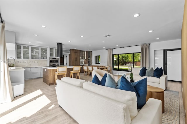 living room with recessed lighting, light wood finished floors, and visible vents