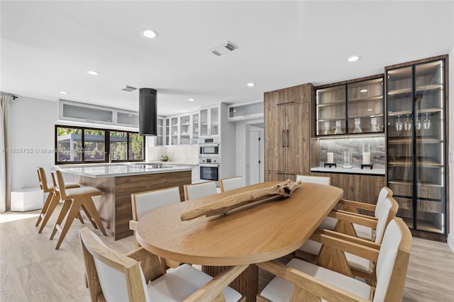 kitchen featuring glass insert cabinets, visible vents, light countertops, and a sink