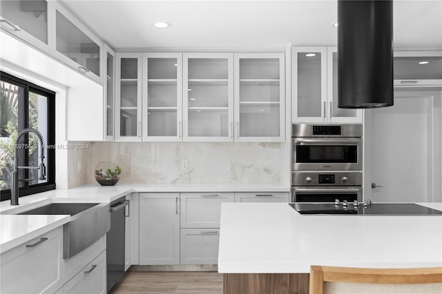 kitchen featuring white cabinetry, sink, stainless steel appliances, light hardwood / wood-style flooring, and decorative backsplash