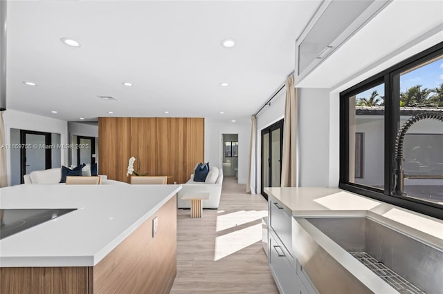 kitchen with white cabinets, a sink, light countertops, light wood finished floors, and stainless steel appliances