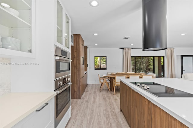 kitchen with light wood-style flooring, black electric stovetop, light countertops, and modern cabinets