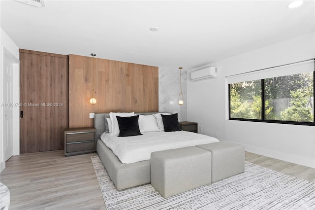 bedroom with light hardwood / wood-style flooring, wooden walls, and a wall mounted AC