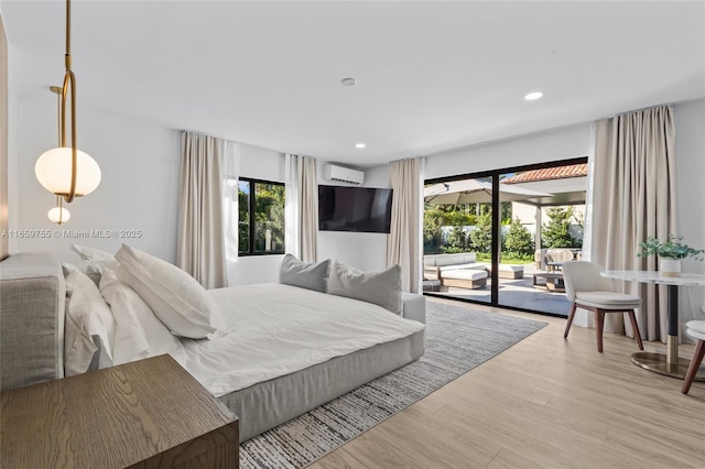bedroom with access to outside, a wall mounted air conditioner, recessed lighting, and light wood-style floors