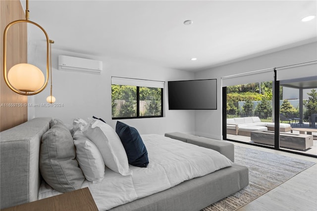 bedroom with access to outside, a wall mounted AC, wood-type flooring, and multiple windows