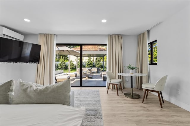 bedroom with recessed lighting, light wood-type flooring, access to exterior, and a wall unit AC