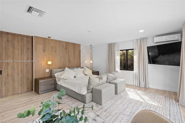 bedroom featuring visible vents, an AC wall unit, and wood finished floors