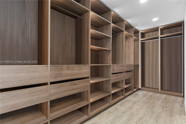 walk in closet with light wood-style flooring