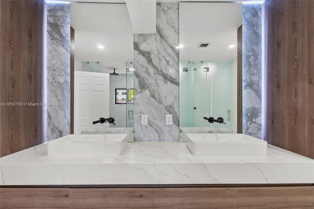 full bath featuring vanity, visible vents, and a marble finish shower
