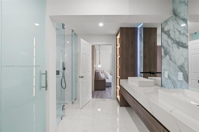 ensuite bathroom featuring marble finish floor, a marble finish shower, a sink, and connected bathroom