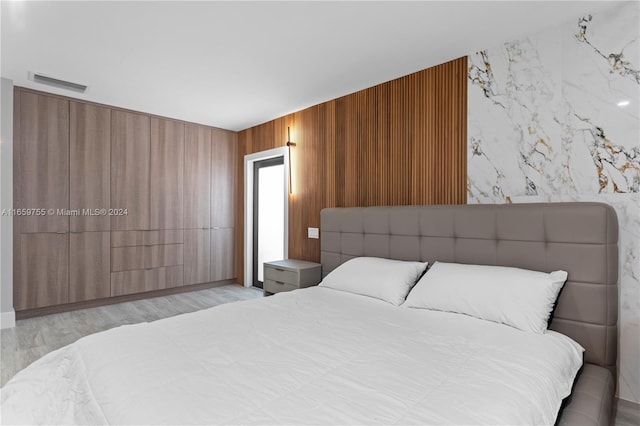 bedroom featuring wood walls and light wood-type flooring