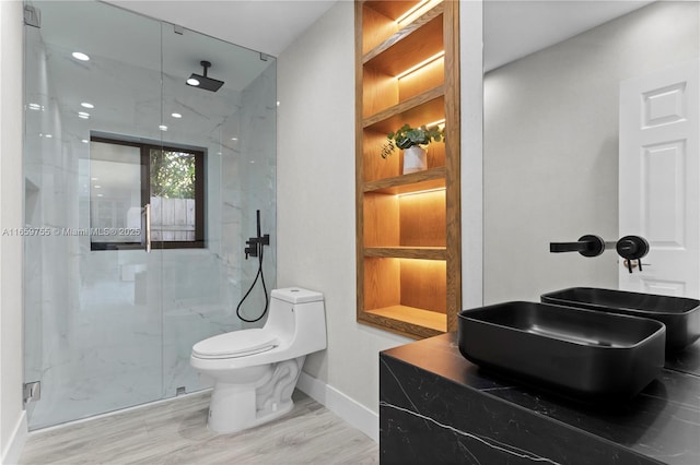 bathroom featuring toilet, wood finished floors, a marble finish shower, and baseboards