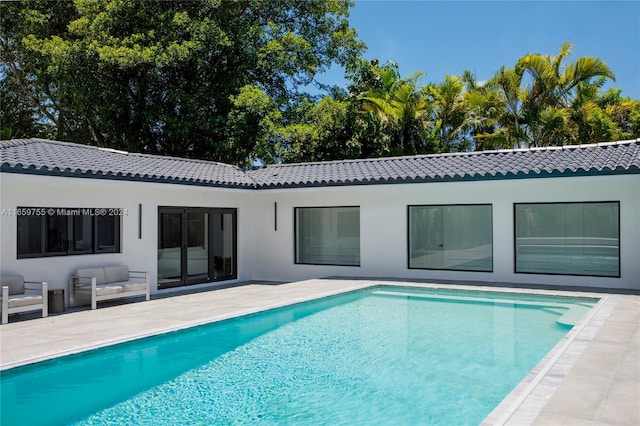 rear view of property with an outdoor living space and a patio