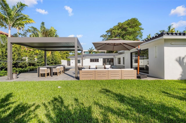 rear view of house with a yard, a patio, stucco siding, and an outdoor hangout area
