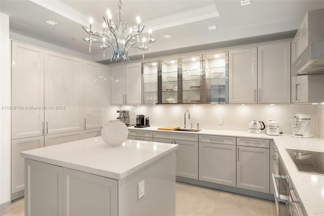 kitchen with sink, a kitchen island, wall chimney range hood, oven, and a raised ceiling