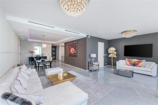 living room featuring a notable chandelier, marble finish floor, baseboards, and a tray ceiling