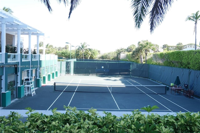 view of tennis court with fence and a pergola