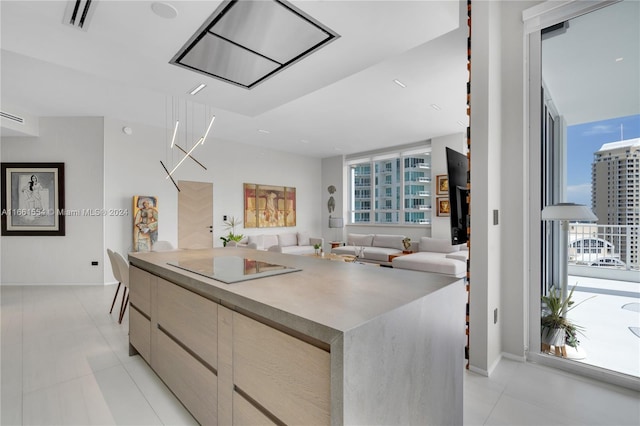 kitchen with a center island, light brown cabinetry, light tile patterned flooring, and black electric cooktop