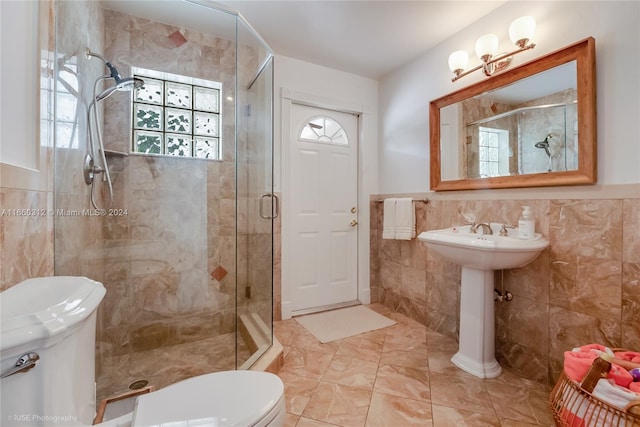 bathroom with tile walls, a shower with door, and toilet