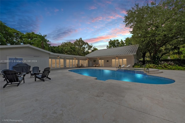 pool at dusk featuring a patio area