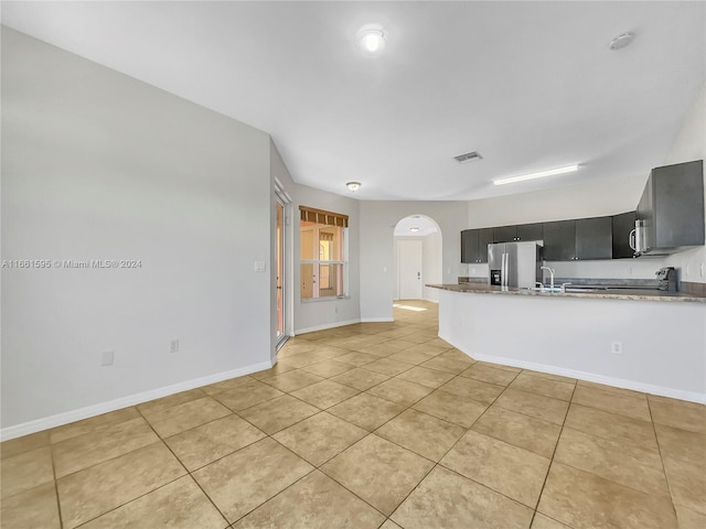 kitchen with stainless steel fridge, kitchen peninsula, and light tile patterned flooring