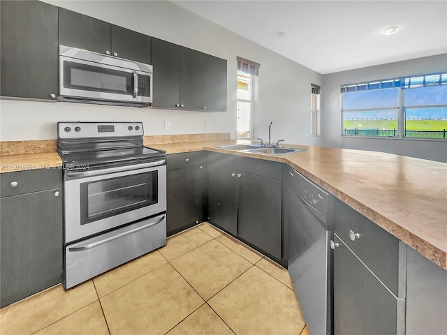 kitchen featuring stainless steel appliances, light tile patterned floors, a healthy amount of sunlight, and sink