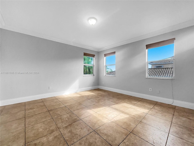 tiled spare room featuring ornamental molding