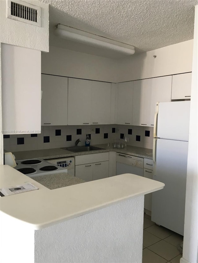 kitchen with backsplash, white appliances, white cabinetry, and sink