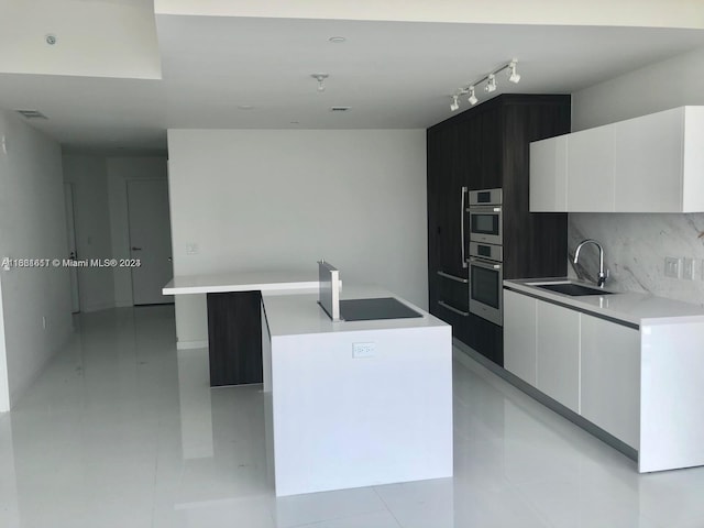 kitchen with a kitchen island, white cabinetry, sink, and tasteful backsplash