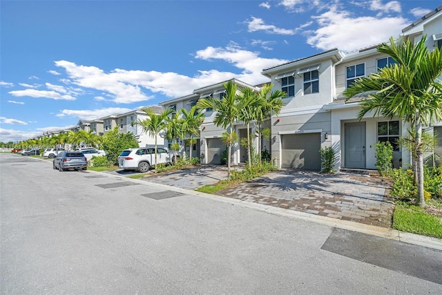 view of property with a residential view, stucco siding, decorative driveway, and a garage