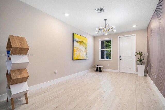 spare room featuring an inviting chandelier and light hardwood / wood-style floors