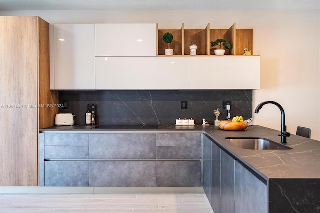 kitchen featuring dark stone counters, white cabinetry, tasteful backsplash, and sink