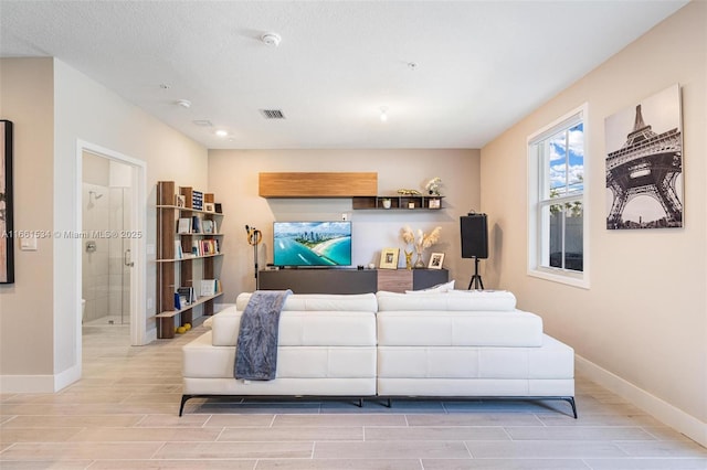 living room with baseboards, visible vents, and wood finish floors