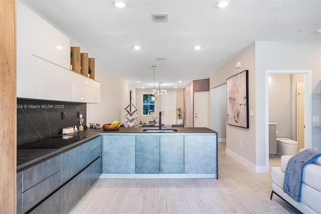 kitchen featuring visible vents, a sink, dark countertops, a peninsula, and black electric stovetop