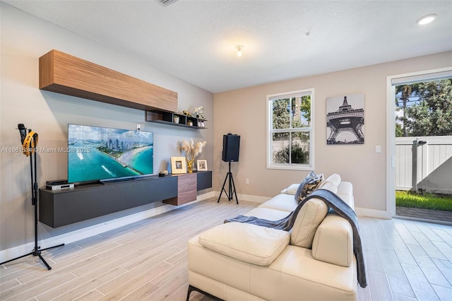 living area featuring recessed lighting, baseboards, and light wood-type flooring