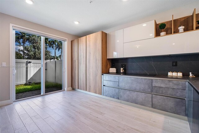 kitchen featuring white cabinets, light hardwood / wood-style flooring, and tasteful backsplash