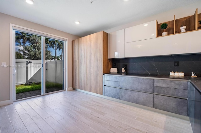 kitchen featuring open shelves, light wood-style flooring, dark countertops, modern cabinets, and tasteful backsplash