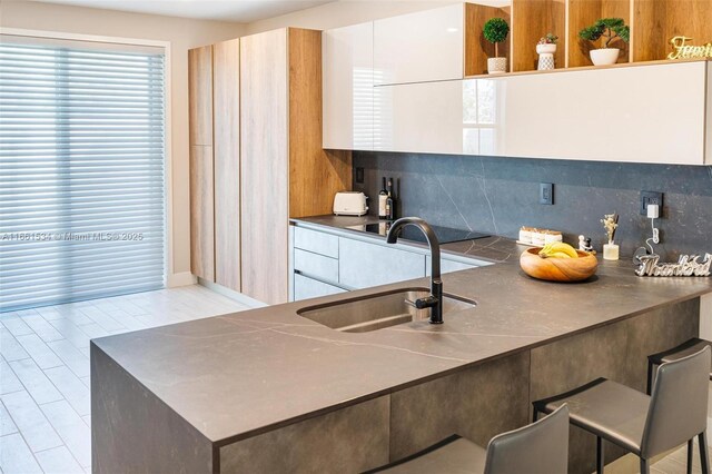 kitchen with white cabinets, sink, and tasteful backsplash