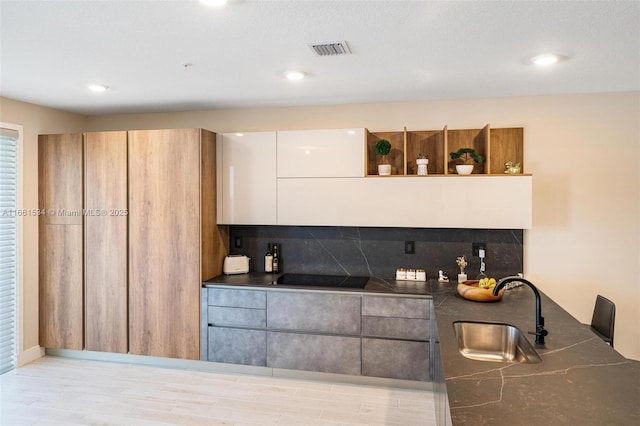 bar featuring black electric cooktop, visible vents, backsplash, and a sink