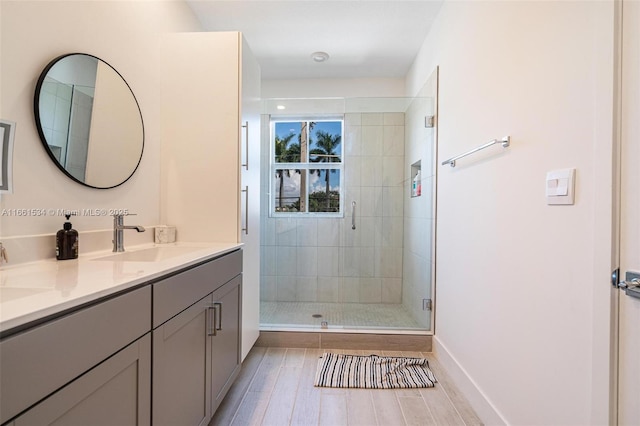 full bath with a shower stall, wood finished floors, double vanity, and a sink