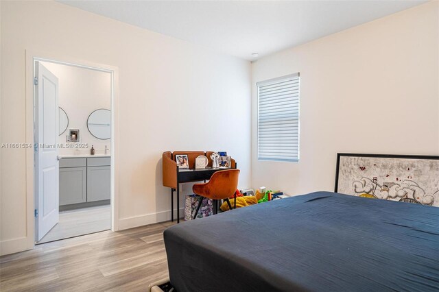 bedroom featuring light hardwood / wood-style flooring and ensuite bath