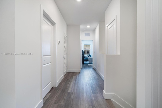 hallway featuring dark wood finished floors, baseboards, and visible vents