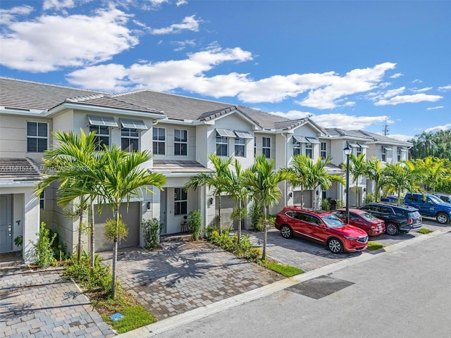 multi unit property with stucco siding, a residential view, uncovered parking, and a tiled roof