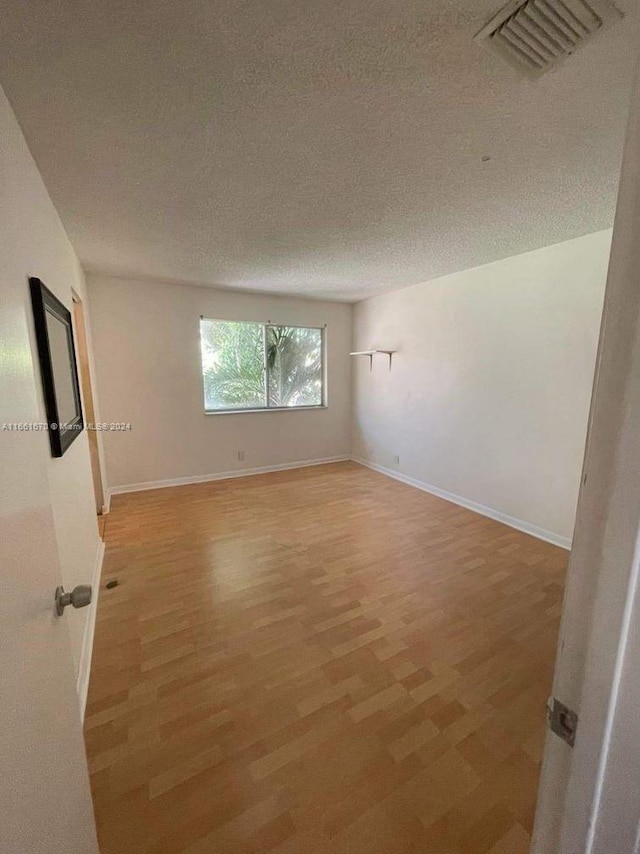 spare room with a textured ceiling and hardwood / wood-style flooring